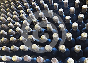 Old dirty wine bottles stacked up in cellar