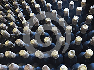 Old dirty wine bottles stacked up in cellar