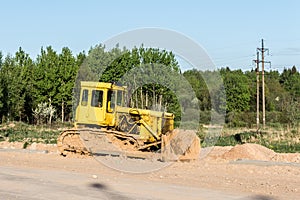 The old dirty yellow bulldozer, road construction in the forest