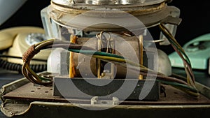 Old disassembled rotary telephone with internal parts on black background. Macro shot of vintage broken analog phone