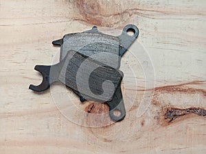 Old disc brake pads of motorcycle isolated on wooden background closeup.