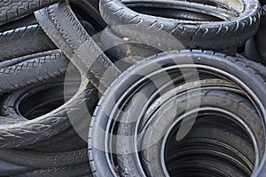 Old discard black motorcycle tire heap in light