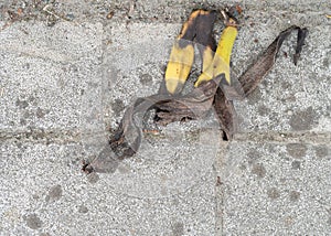 Old discarded banana skin on grubby pavement, sidewalk. Not biodegrading quickly.