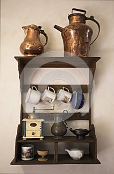 Old dishes. Historical cookware. Old hunged on wooden shelf on medieval wall.