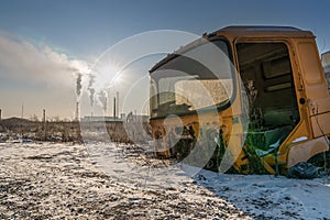 An old dismantled truck cab, abandoned in a junkyard. on the background of dy from the factory pipes. dull and