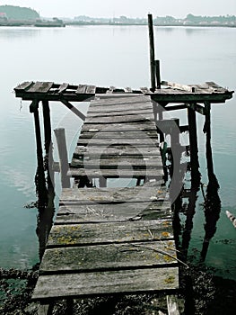 Old dock floating in foggy weather with town showing up in the background