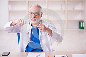 Old male doctor wearing mask in the clinic