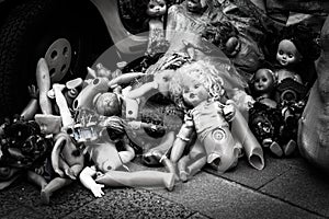 Old dolls dumped in a heap at the yellow car, trash of children`s toys