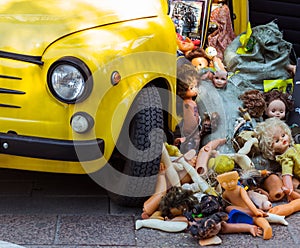 Old dolls dumped in a heap at the yellow car, trash of children`s toys