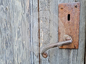 Old rusted door handle on a wooden door