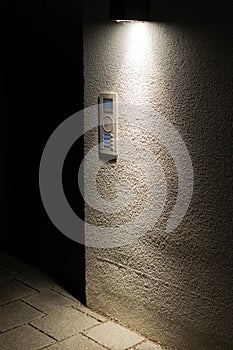 Old door bell with intercom illuminated at night