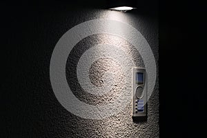 Old door bell with intercom illuminated at night, close up