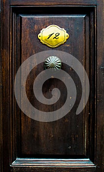 Old door with the door handle and nameplate with number
