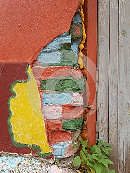 The old door frame and part of the adjacent brick wall with stucco are painted in bright colors from the side of the street.