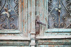 Old door handle close up. Metal handle and door lock of an old wooden door. Vintage green wooden door with metal lattice