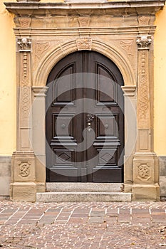 Old door of a historical building with statues and coats of arms made of stone