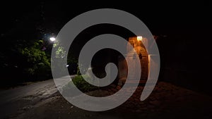 The old door is illuminated by a street lamp, next to the road.