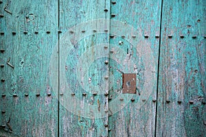 Old door with metal ornaments on bluish green painted natural wood