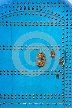 Old door with golden nails, on the house on a blue painted street in the medina of Chefchaouen, Morocco