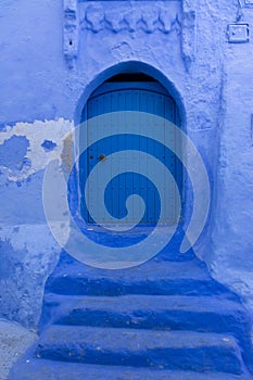 Old door of a house on a street painted blue in the medina of Chefchaouen, Morocco