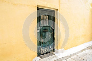 Old door of residential building in Plaka district, Athens, Greece. Traditional house with yellow wall and grunge door on vintage