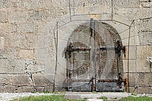 An old door on a stone wall of an 18th century fortress in Italy