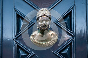 Old doorknob in the form of man head on a blue door