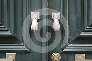 Old doorknocker with hand shape on old wooden door
