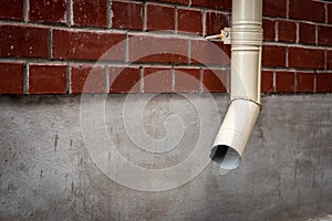 Old drain pipe on the brown brick wall. Downspout