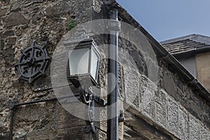 Old drain pipe and carriage light attached to a wall