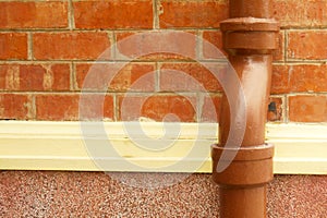 The old drain pipe with frozen water against the wall