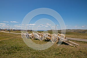 Old dray in Huanghuagou Huitengxile grassland near Hohhot, Inner Mongolia, China, with yurts and wind turbine in distance