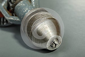 Old drill chuck of an old hand drill on a gray