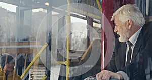 Old driver greeting passengers on bus.