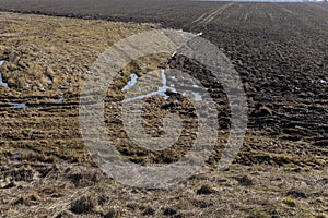 old dry grass and arable land in early spring after snowmelt