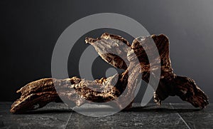 Old dry wooden snag on a black stone table