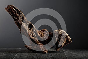 Old dry wooden snag on a black stone table