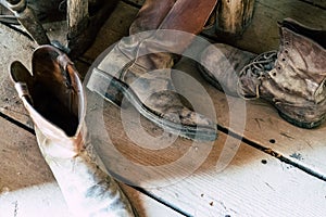 Old dusty dirty cowboy boots sitting on a wooden floor