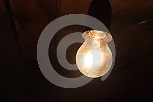 Old dusty light bulb glowing in the dark