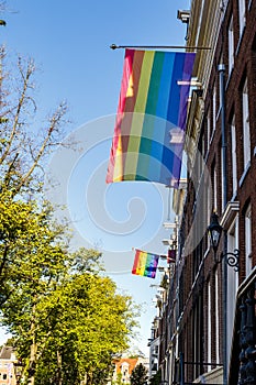 Old Dutch canal houses in Amsterdam with a Pride Flag on their facades during Gay Pride Amsterdam