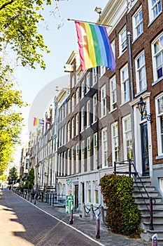 Old Dutch canal houses in Amsterdam with a Pride Flag on their facades during Gay Pride Amsterdam