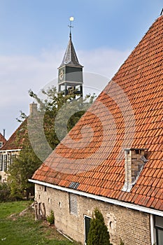 Old dutch farmhouse with churchtower behind it