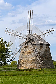 Old Dutch windmill. Built in 1880-1885. Standing on a green meadow with blue sky and clouds