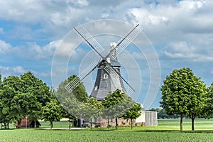 Old dutch windmill with cloudy sky and trees
