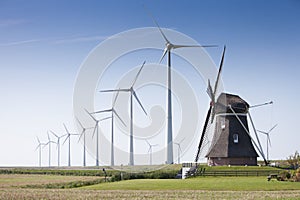 Old dutch windmill and modern wind turbines against blue sky in dutch province of groningen