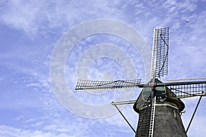 Old Dutch windmill from the year 1776 with blue cloudy sky and flying birds, Zwolle, The Netherlands