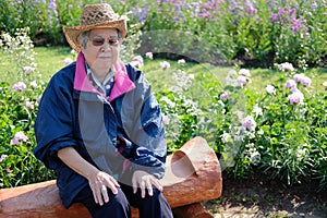 Old elder woman resting in garden. elderly female relaxing outdoors. senior leisure lifestyle