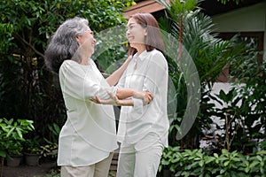 An old elderly Asian woman and dance in the backyard with her daughter.  Concept of happy retirement With care from a caregiver
