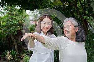 An old elderly Asian woman and exercise in the backyard with her daughter.  Concept of happy retirement With care from a caregiver