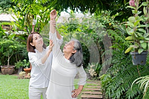 An old elderly Asian woman and exercise in the backyard with her daughter.  Concept of happy retirement With care from a caregiver